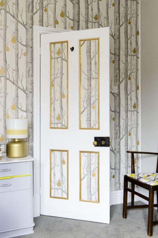 cole and sons wallpaper in the panels of a white door with a gold trim